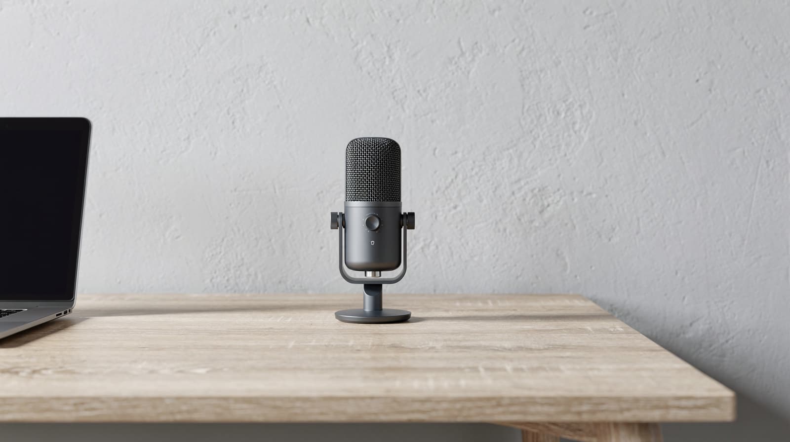 Charcoal USB microphone on a desktop stand beside a laptop